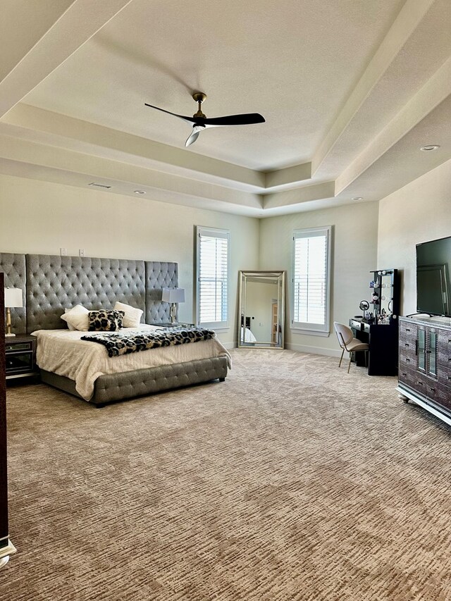 bedroom featuring a tray ceiling, baseboards, a ceiling fan, and carpet flooring