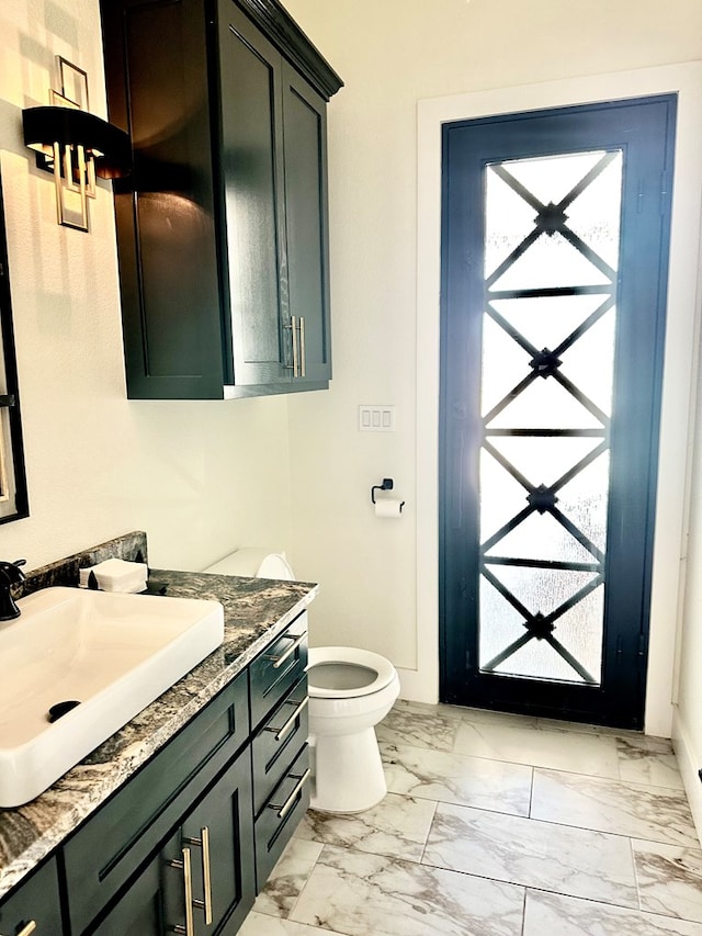 half bath with baseboards, toilet, marble finish floor, and vanity