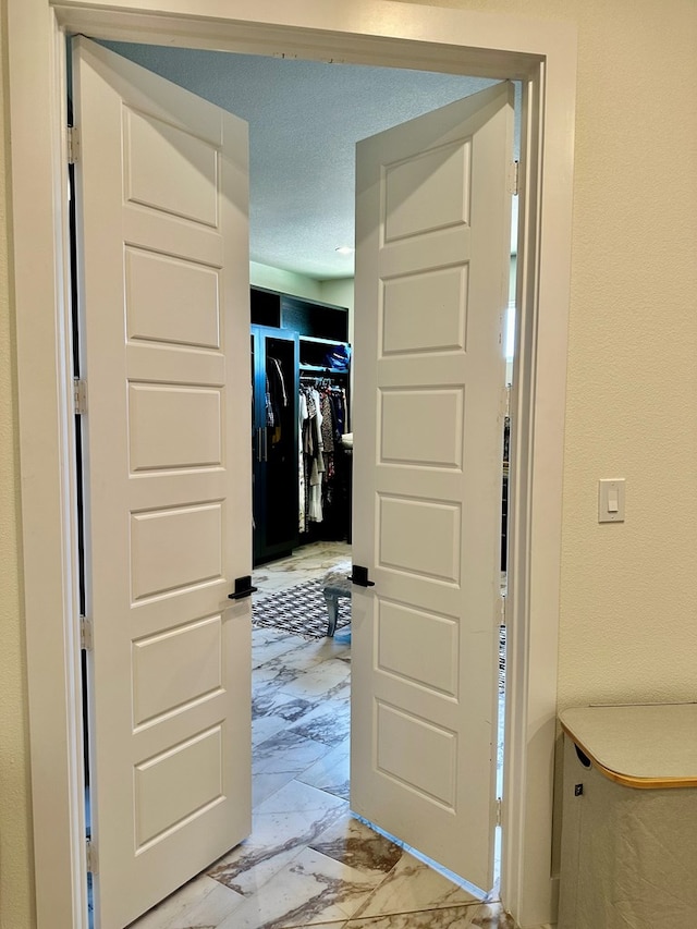 hall featuring a textured ceiling and marble finish floor