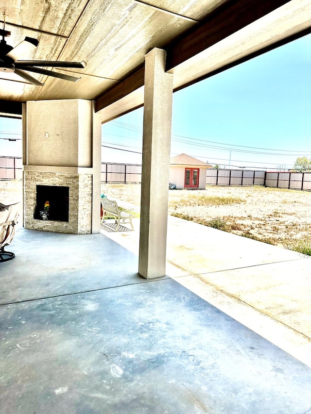 view of patio / terrace featuring exterior fireplace, an outbuilding, and a fenced backyard