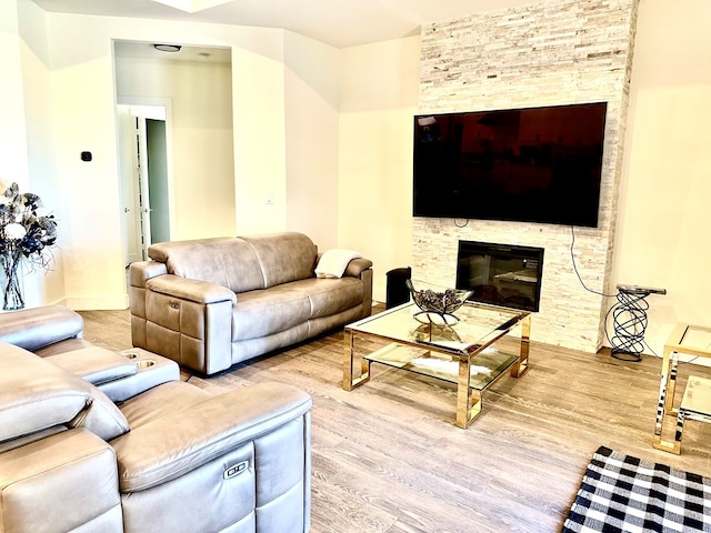 living area featuring a stone fireplace and wood finished floors