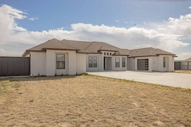 view of front of property featuring a patio, fence, driveway, an attached garage, and stucco siding