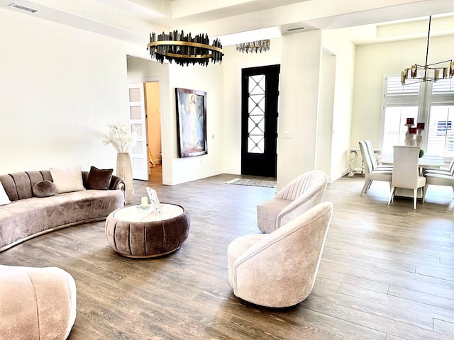 living room with a chandelier, baseboards, visible vents, and wood finished floors