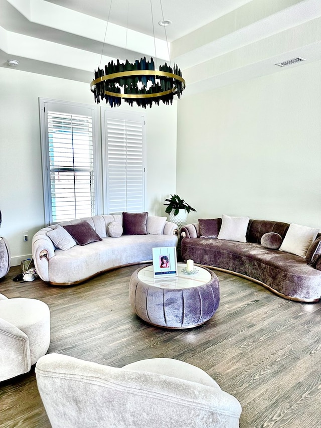 living room featuring a raised ceiling, wood finished floors, and visible vents