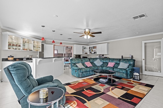 living room with a textured ceiling, ceiling fan, light tile patterned floors, and crown molding