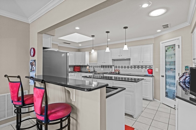 kitchen with a kitchen breakfast bar, backsplash, crown molding, white cabinetry, and hanging light fixtures