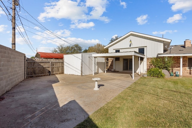 rear view of property with a lawn, a patio area, and a shed