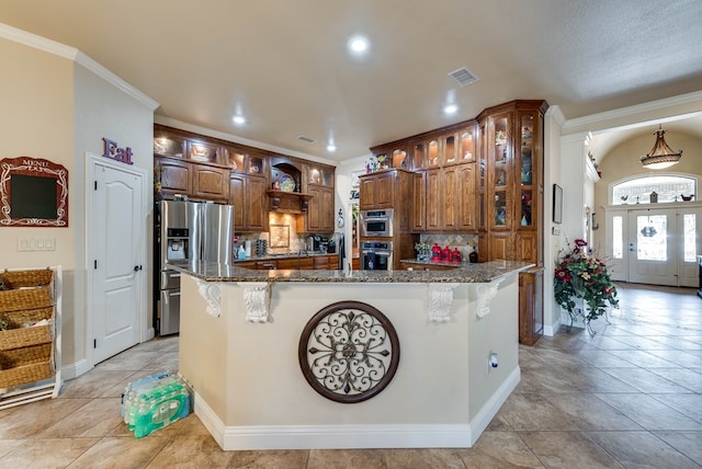 kitchen with appliances with stainless steel finishes, a breakfast bar area, dark stone countertops, and an island with sink