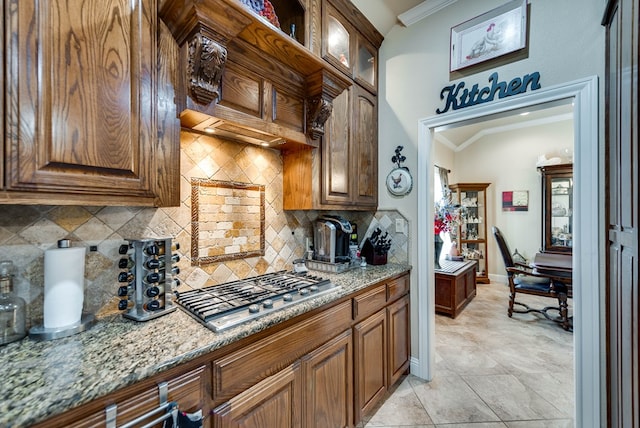 kitchen featuring decorative backsplash, light stone countertops, vaulted ceiling, crown molding, and stainless steel gas stovetop