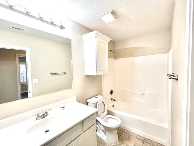 full bathroom with washtub / shower combination, vanity, tile patterned flooring, and toilet