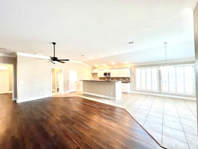 unfurnished living room featuring crown molding, light hardwood / wood-style flooring, and ceiling fan with notable chandelier