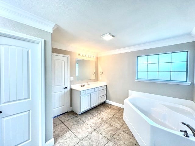 bathroom featuring tile patterned floors, a tub, crown molding, and vanity