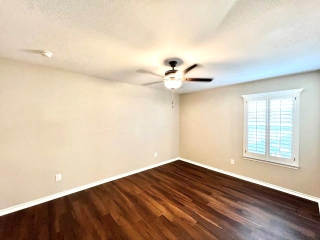 empty room featuring ceiling fan, dark hardwood / wood-style flooring, and a textured ceiling