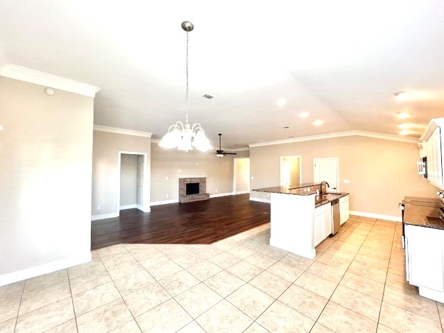 kitchen featuring ceiling fan with notable chandelier, crown molding, pendant lighting, dishwasher, and white cabinetry