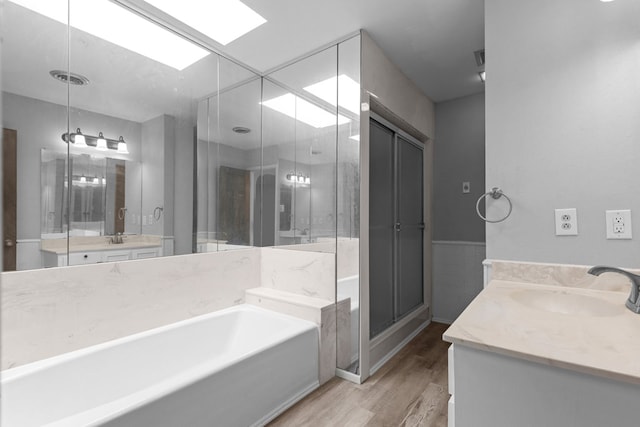 bathroom featuring hardwood / wood-style flooring, a skylight, tile walls, shower with separate bathtub, and vanity