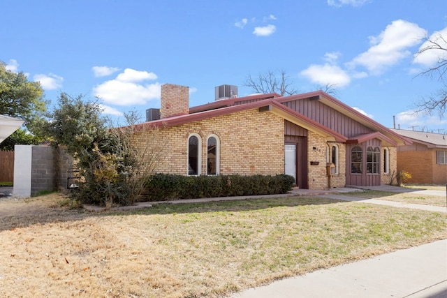 view of front of property with a front yard and central AC unit