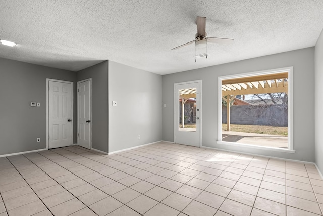 tiled empty room with ceiling fan and a textured ceiling