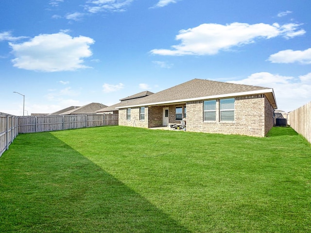 rear view of house with central AC unit and a lawn