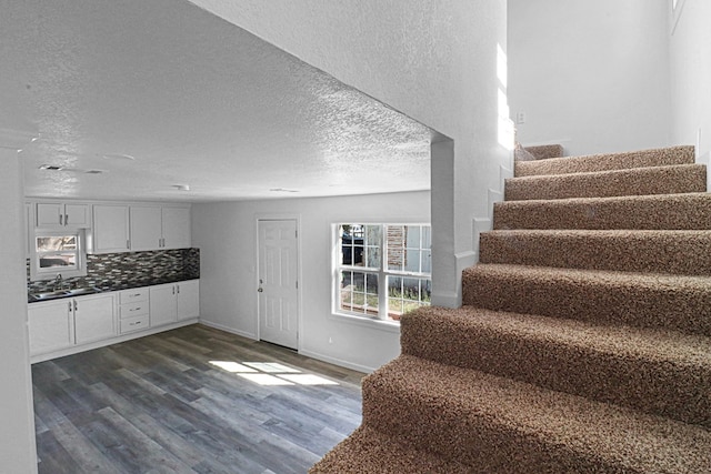 stairway with hardwood / wood-style flooring, sink, and a textured ceiling