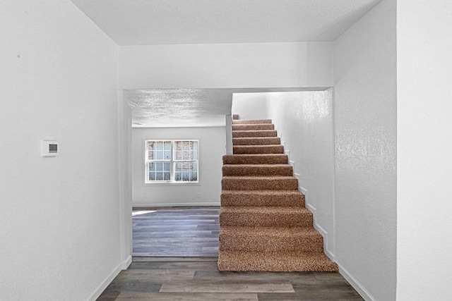 stairs featuring wood-type flooring and a textured ceiling