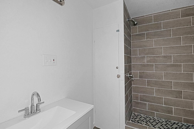 bathroom with tiled shower and vanity