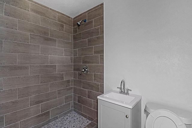 bathroom with vanity, toilet, and a tile shower