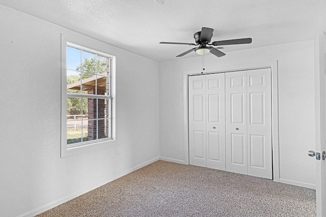 unfurnished bedroom with a textured ceiling, a closet, ceiling fan, and carpet flooring