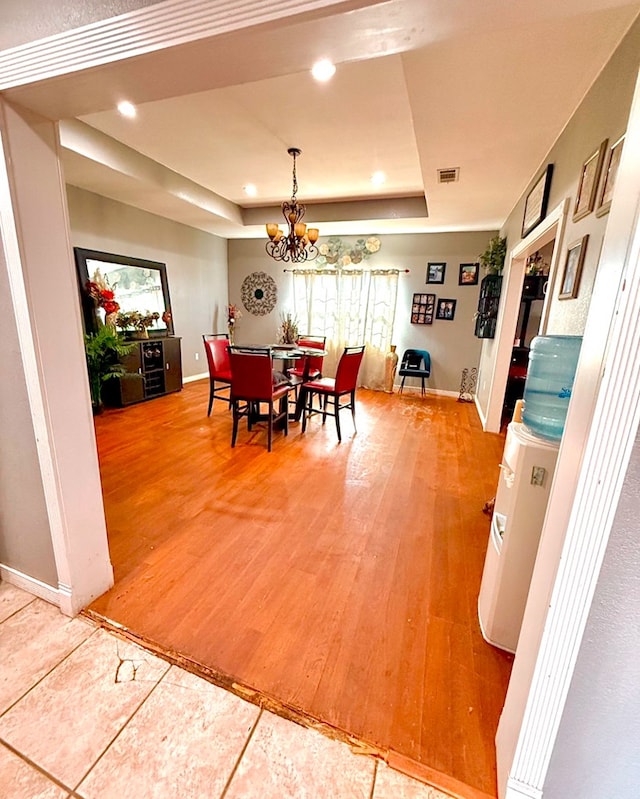 dining area with a tray ceiling, hardwood / wood-style flooring, and a chandelier