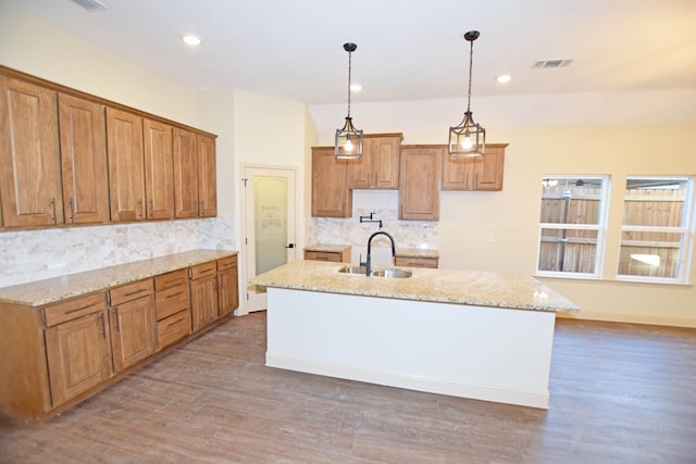 kitchen featuring a center island with sink, decorative backsplash, pendant lighting, and sink