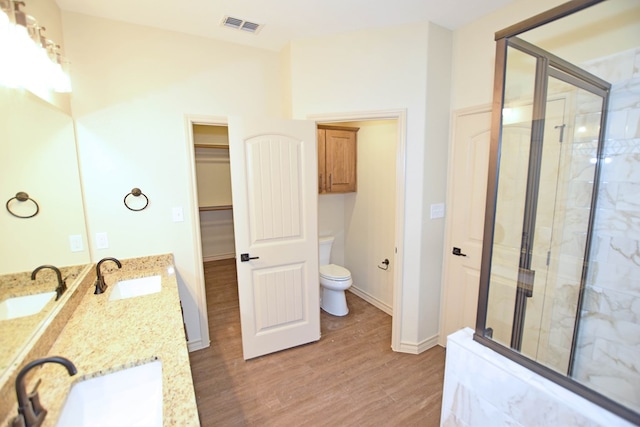 bathroom with hardwood / wood-style floors, vanity, toilet, and a shower with shower door