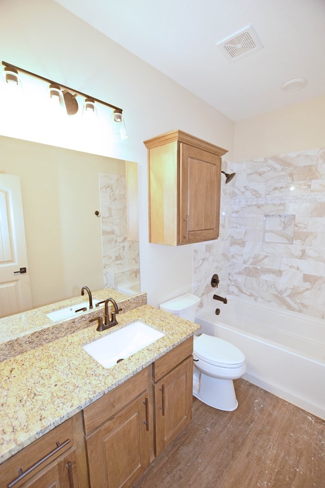 full bathroom featuring hardwood / wood-style floors, vanity, toilet, and tiled shower / bath