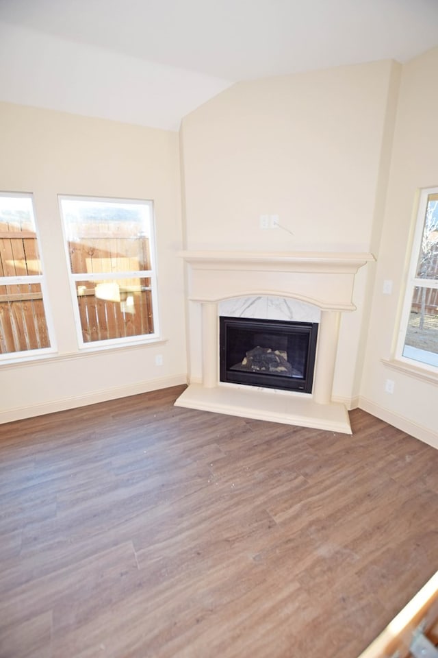 unfurnished living room featuring lofted ceiling, a high end fireplace, and dark hardwood / wood-style floors