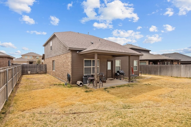 back of house featuring a patio area, a yard, brick siding, and a fenced backyard