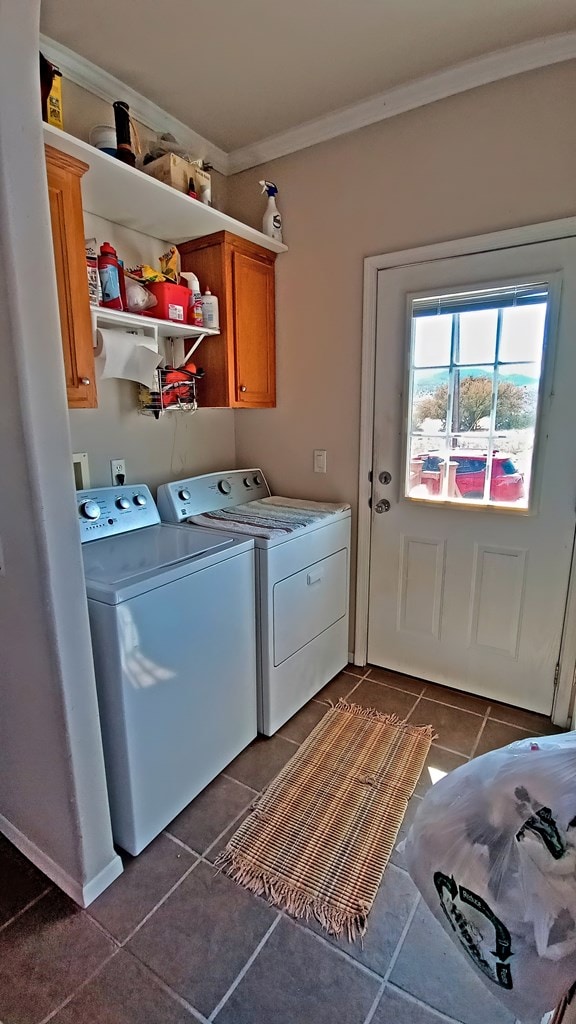 clothes washing area with cabinets, crown molding, dark tile patterned floors, and washer and dryer