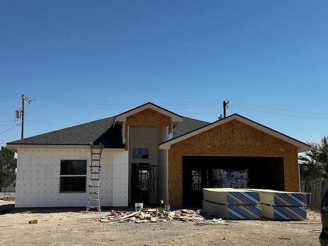 property in mid-construction featuring a garage and roof with shingles