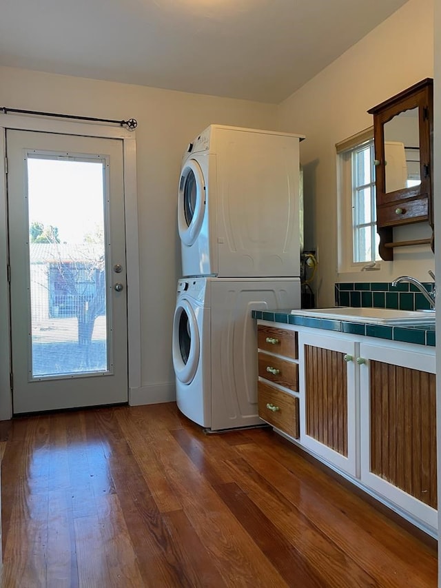 washroom featuring hardwood / wood-style flooring, stacked washer / drying machine, plenty of natural light, and sink