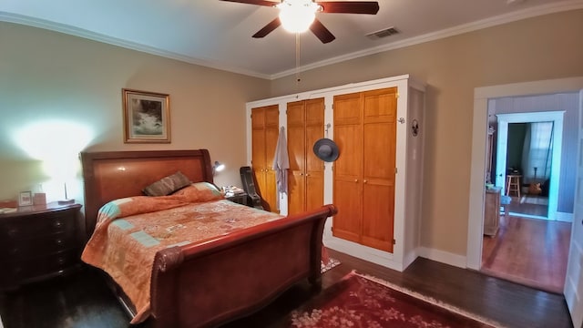 bedroom with dark hardwood / wood-style flooring, two closets, ceiling fan, and ornamental molding