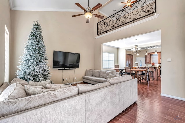 living room with crown molding, a towering ceiling, and ceiling fan with notable chandelier