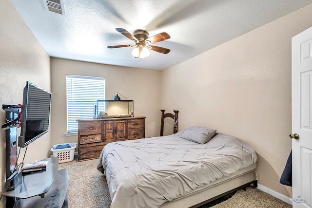 carpeted bedroom with ceiling fan and a textured ceiling