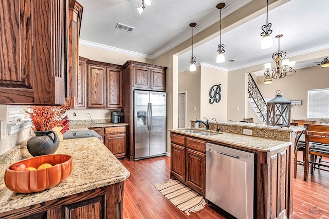 kitchen featuring appliances with stainless steel finishes, a textured ceiling, sink, pendant lighting, and a center island