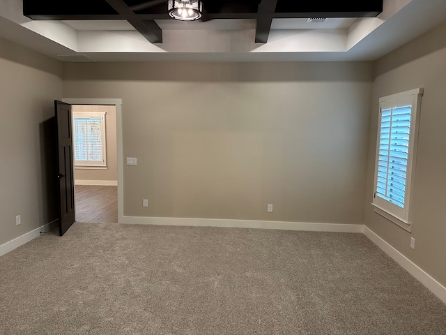 carpeted empty room featuring beam ceiling and coffered ceiling