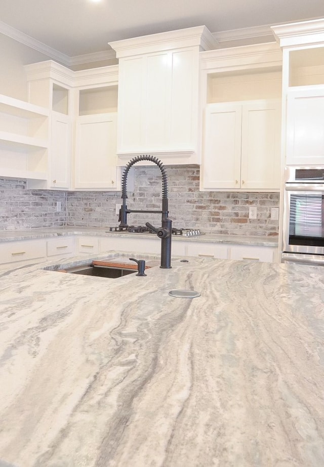 kitchen with white cabinets, tasteful backsplash, and stainless steel oven