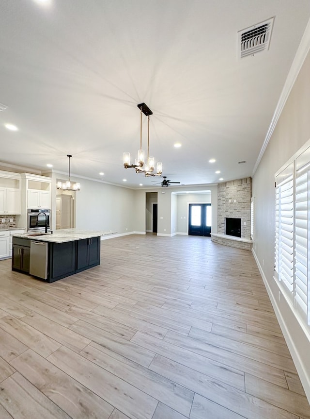 interior space featuring pendant lighting, ceiling fan with notable chandelier, stainless steel dishwasher, and white cabinetry