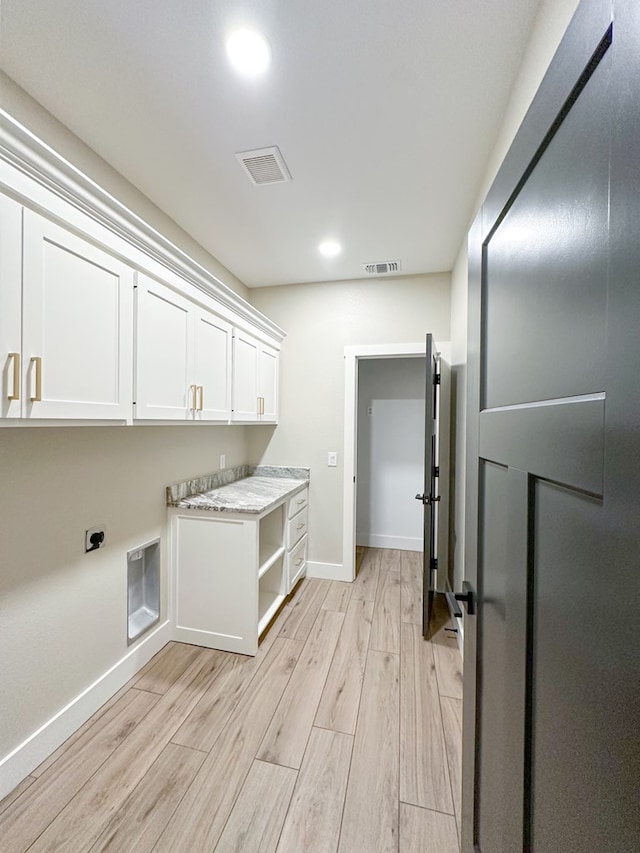 laundry area with hookup for an electric dryer, light hardwood / wood-style floors, and cabinets