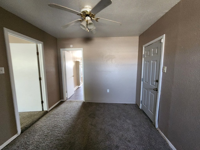 unfurnished room with ceiling fan, dark carpet, and a textured ceiling