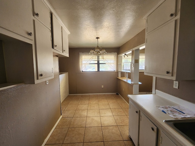 kitchen featuring sink, light tile patterned floors, decorative light fixtures, a notable chandelier, and white cabinetry