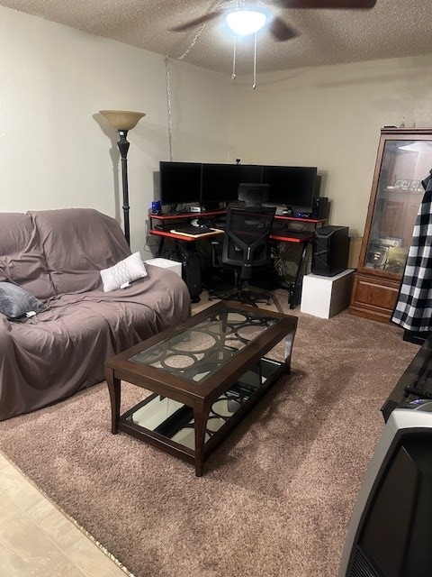 carpeted living area featuring ceiling fan and a textured ceiling