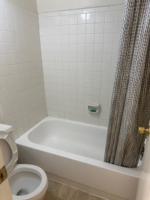 bathroom featuring shower / bath combination with curtain, tile patterned flooring, and toilet