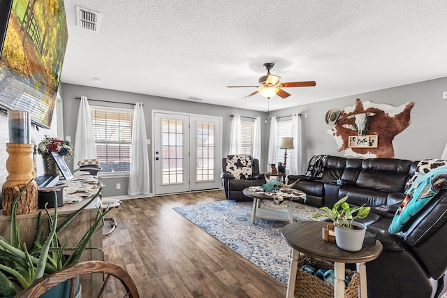 living room with ceiling fan, a textured ceiling, and hardwood / wood-style flooring