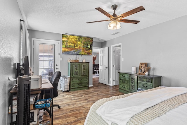 bedroom featuring access to exterior, ceiling fan, dark hardwood / wood-style flooring, and a textured ceiling